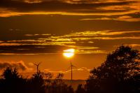 Image: sun setting over windmills. Article: Dark Cloud Looms Over Amazon’s Innovation Challenge