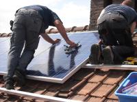 Image: workers attaching solar panels to a house. Title: Make Solar Power Affordable Now