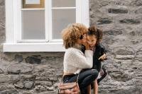 mother holding daughter outside of home. 