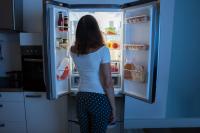 Image: woman looking in fridge at night. Topic: 5 Ways to Fight Food Waste