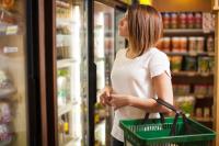 woman in grocery store standing in front of a refrigerator, where refrigerant management needs to be improved