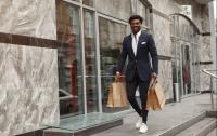 black man in suit walking with paper bags in hand. 