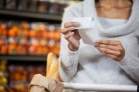 Image: shopper in a grocery store holding a receipt. Title: What do People Think of Paper Receipts?