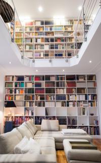 white wooden bookshelves filled with books behind a sectional couch