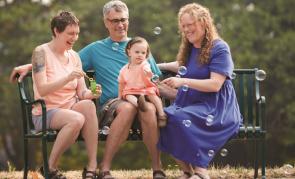 People sitting on a park bench blowing bubbles