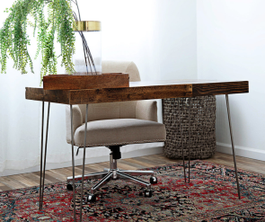 Reclaimed wood desktop with hairpin legs on stylish rug in front of a cream upholstered rolling chair 