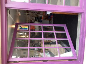 Purple window with queer/trans pride flag on it that shows into the office