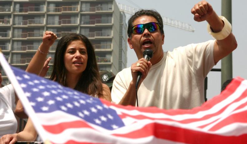 Image: two people at rally, with American flag in foreground. Topic: A Discussion Guide for Climate Justice