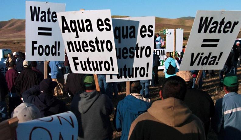 Image: marchers carrying signs, "Agua es nuestro futuro." Title: The Power of Latino Voices in Environmental Justice