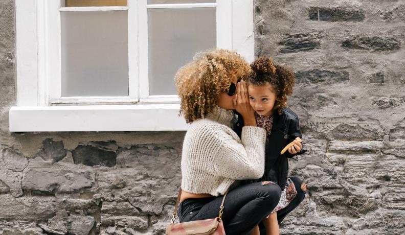 mother holding daughter outside of home. 