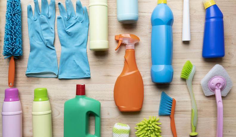 Image: an array of cleaning products on a table. Topic: 13 Toxic Chemicals Lurking in Your Home