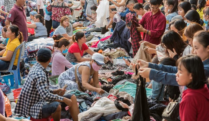 Image: people shop through secondhand clothes at Cho Con Market. Topic: When you donate clothes, they may not go where you think. Learn what really happens to your clothing castoffs.