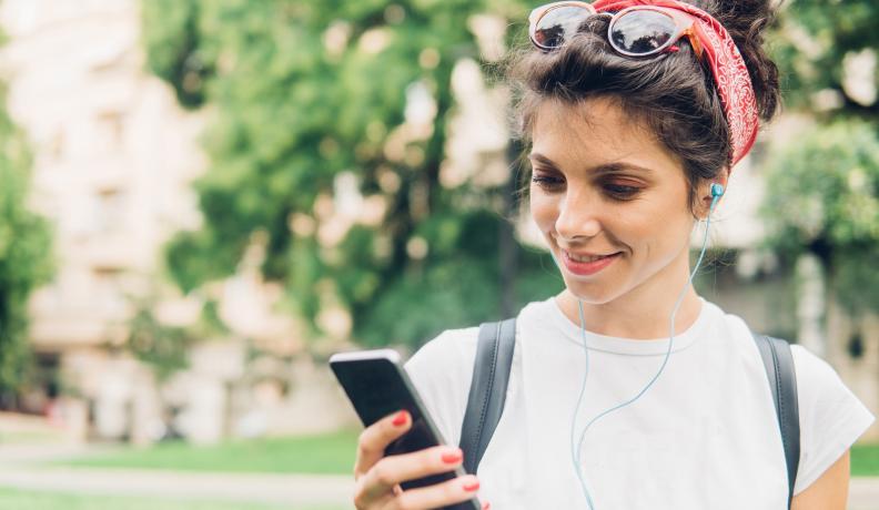 girl standing outside listening to a podcast