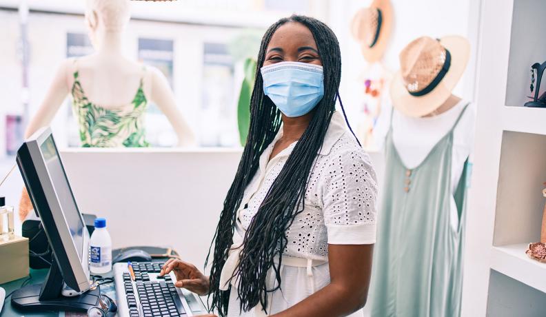 Black woman wearing mask behind cash register