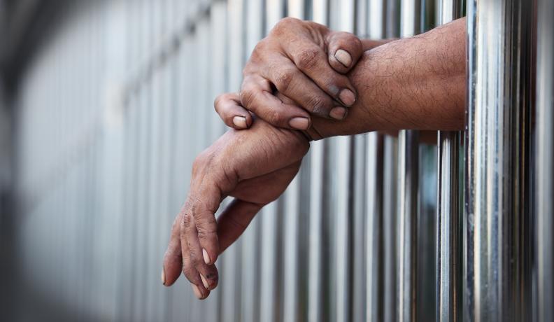 hands hanging out of a prison cell