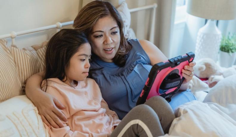 mother and daughter looking at a tablet together and talking