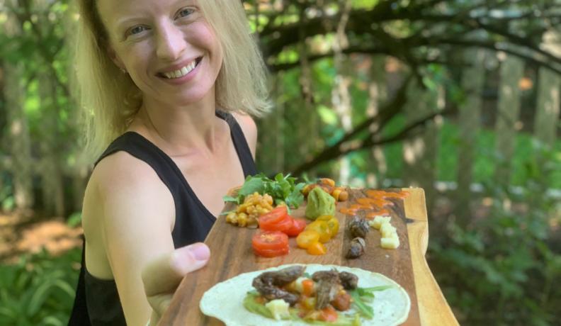 Dr. Cortni Borgerson serves up cicada tacos on a live edge wood cutting board.