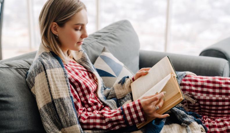 woman reading in red checkered pajamas