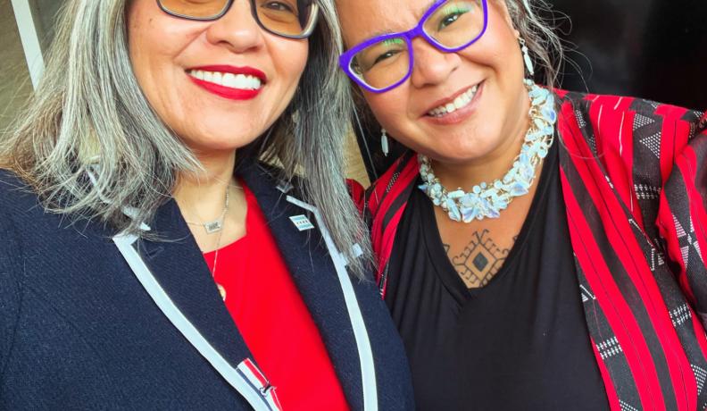 Two Filipino women dressed in business professional, smiling for a selfie.