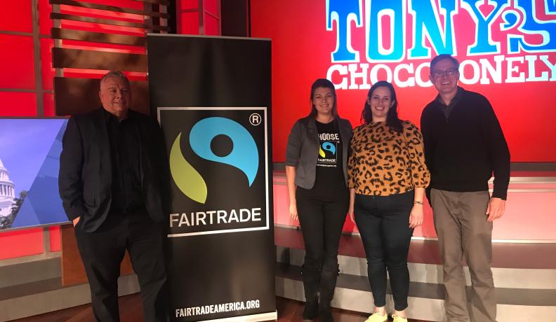 speakers at a Tony's Chocolate event standing next to a fair trade banner.