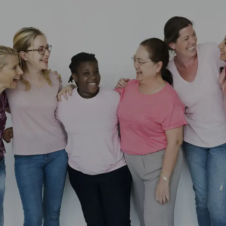 Image: diverse group of women embracing and smiling. Title: Why Investing in  Women Pays Off