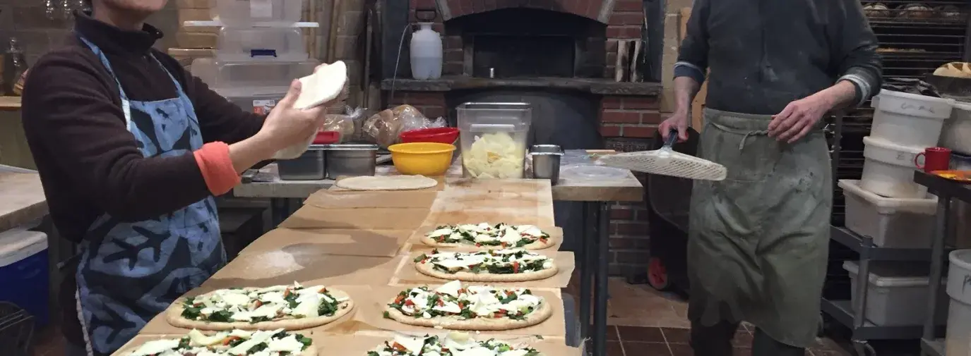 Fawziah Alshehri and Bob O’Neil make fresh, organic pizza in Village Bakery & Café’s kitchen