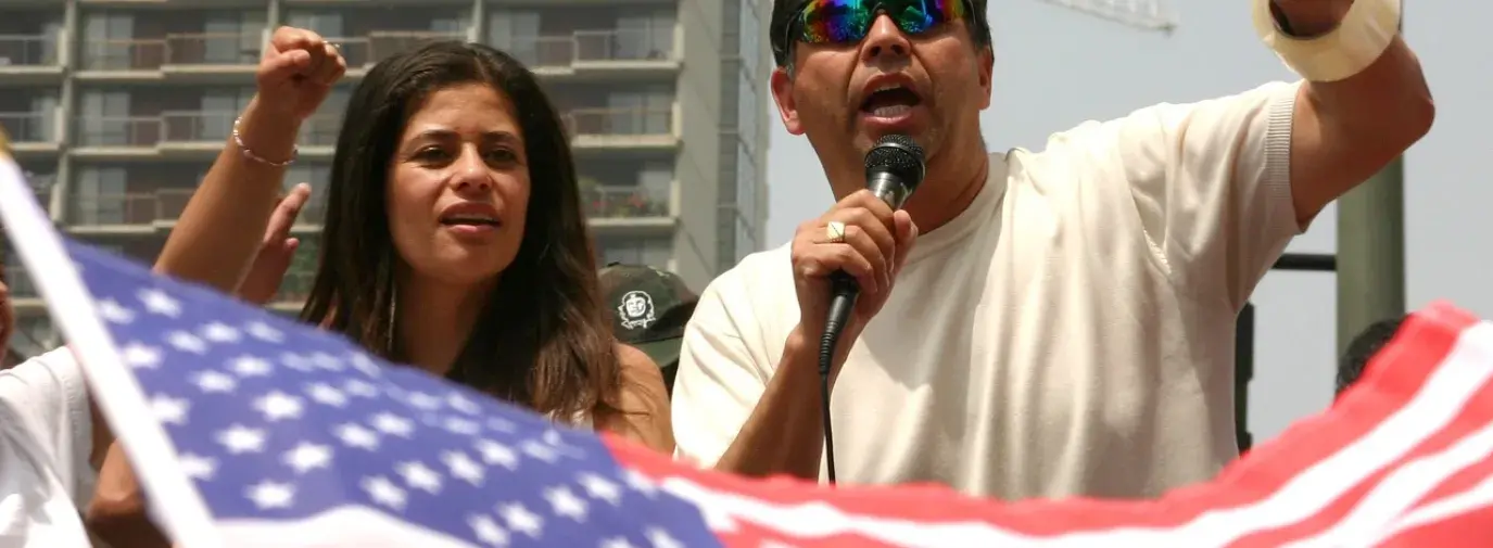 Image: two people at rally, with American flag in foreground. Topic: A Discussion Guide for Climate Justice