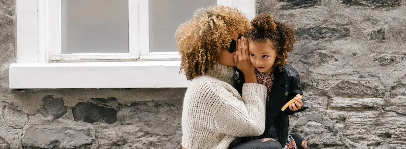 mother holding daughter outside of home. 