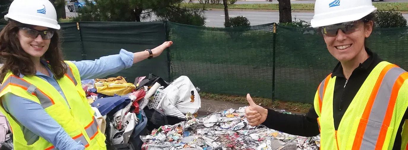 Beth and Kristin stand in front of a bale of materials for recycling