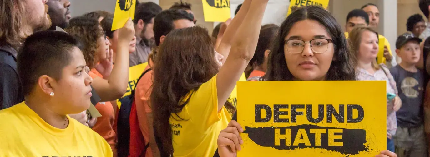 Protestor holds up sign that says "Defund Hate" at protest against ICE