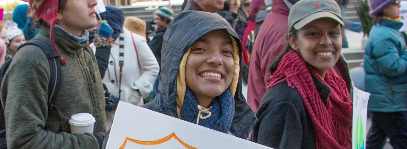 activist with sign that reads "hashtag Votes for Climate"