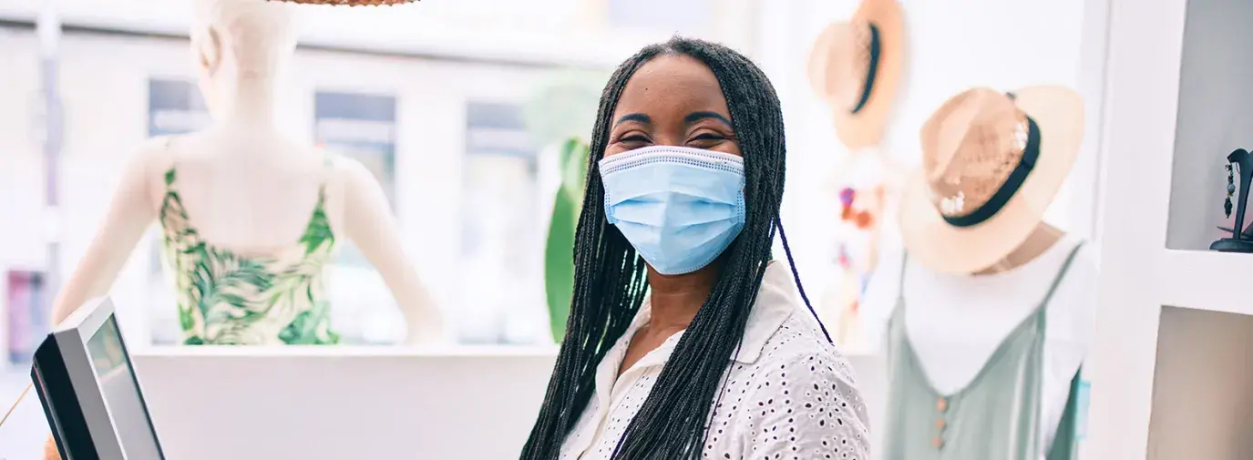 Black woman wearing mask behind cash register