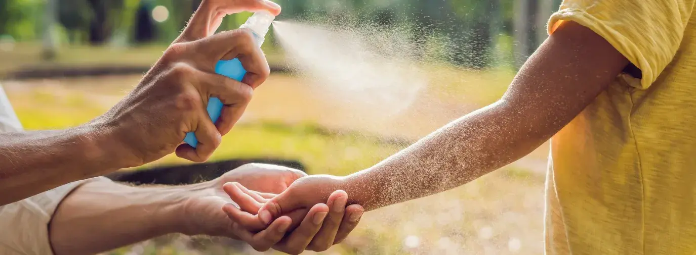 person spraying kid with natural bug spray outdoors