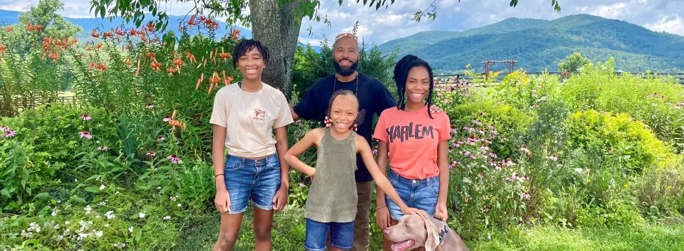 a family stands together with their dog smiling at the camera