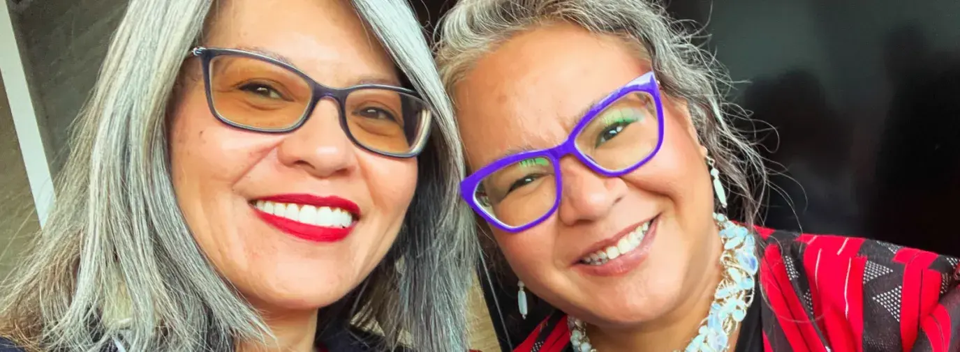 Two Filipino women dressed in business professional, smiling for a selfie.