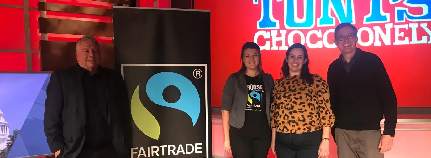 speakers at a Tony's Chocolate event standing next to a fair trade banner.