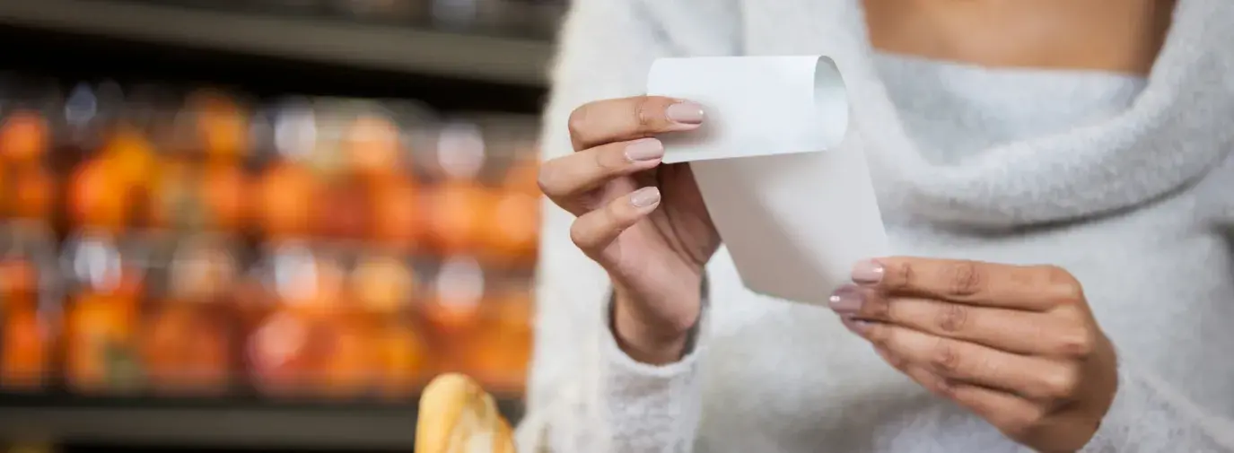 Image: shopper in a grocery store holding a receipt. Title: What do People Think of Paper Receipts?