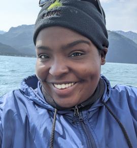 Tye Tavaras smiling at the camera in a blue wind breaker and black beanie