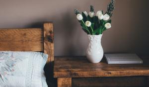 Image: side table with flowers, in bedroom. Topic: The Allergen-Free Bedroom