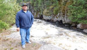 Guy Anahkwet Reiter stands near the Menominee River, which is sacred to the Menominee Tribe.