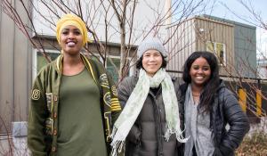 Image: three people stand outside a new housing development. Topic: Turning Crisis into Creation with Green Affordable Housing