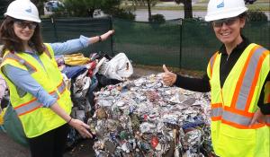 Beth and Kristin stand in front of a bale of materials for recycling