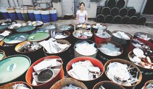 Image: woman standing with full recycling containers. Topic: Americans are bad at recycling. Here's How the World Does It Better.