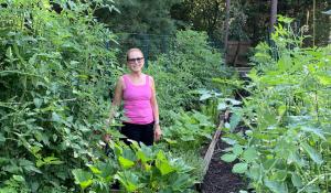 woman in pink shirt stands in lush home garden