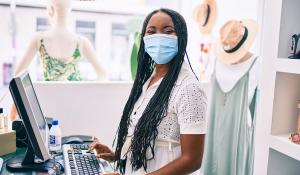 Black woman wearing mask behind cash register