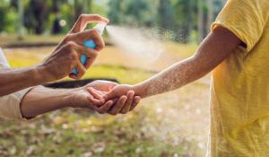 person spraying kid with natural bug spray outdoors