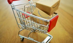 Image: tiny model shopping cart with Amazon boxes. Topic: Amazon Worker Rights: Issues At Home And Abroad