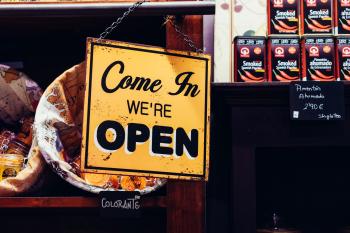 Image: orange sign stating "Come in, we're open." Topic: Free Store: Where Everything Is, Yes, Free