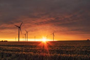 Image: wind turbines in a field against the setting sun. Title: Is Verizon’s Green Bond Tipping the Scales on Clean Energy?