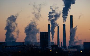 energy plants emitting clouds of pollution against sunset 